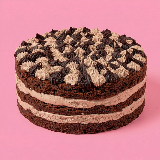 Chocolate cake with white and dark chocolate frosting on a pink background