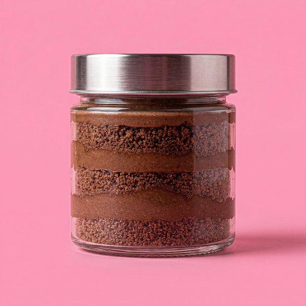Glass jar with layered brown substance on a pink background