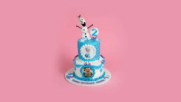Two-tiered birthday cake with Frozen theme on a pink background