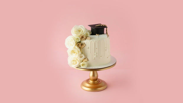 Decorative cake with flowers and a graduation cap on a pink background