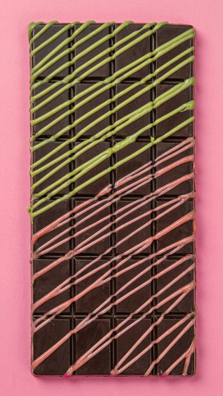 Chocolate bar with green and pink drizzle on a pink background