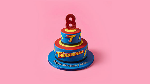 Two-tiered birthday cake with 'Thunderman' branding and number 8 candle on a pink background