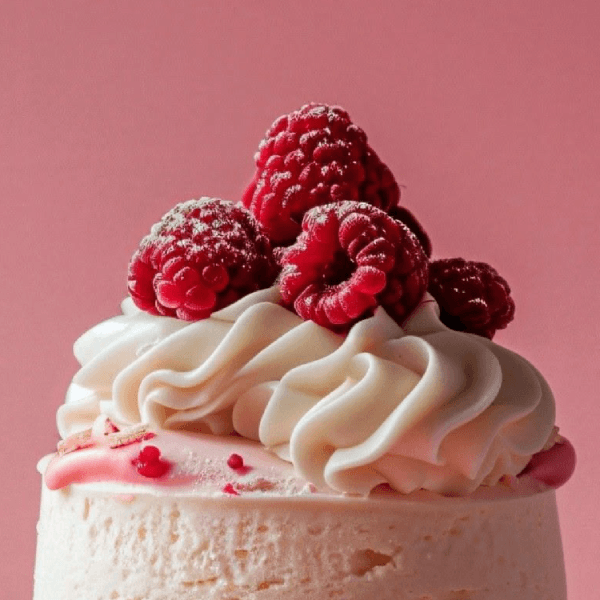 Small cake with white frosting and raspberries on a pink background