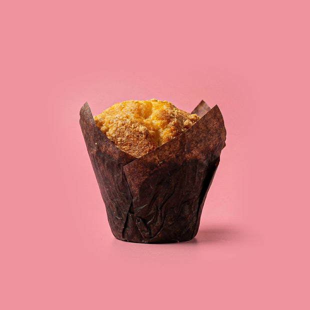 Vegan vanilla muffin in a brown paper cup on a pink background